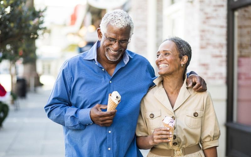 Close to the center of everything older couple walks down city sidewalk while holding ice cream cones
